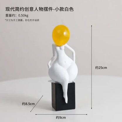 A modern minimalist white resin abstract art female figurine with a glossy yellow sphere on a black base by decorbites
