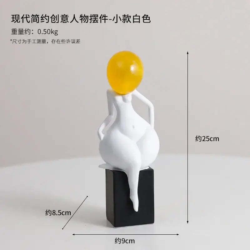 A modern minimalist white resin abstract art female figurine with a glossy yellow sphere on a black base by decorbites