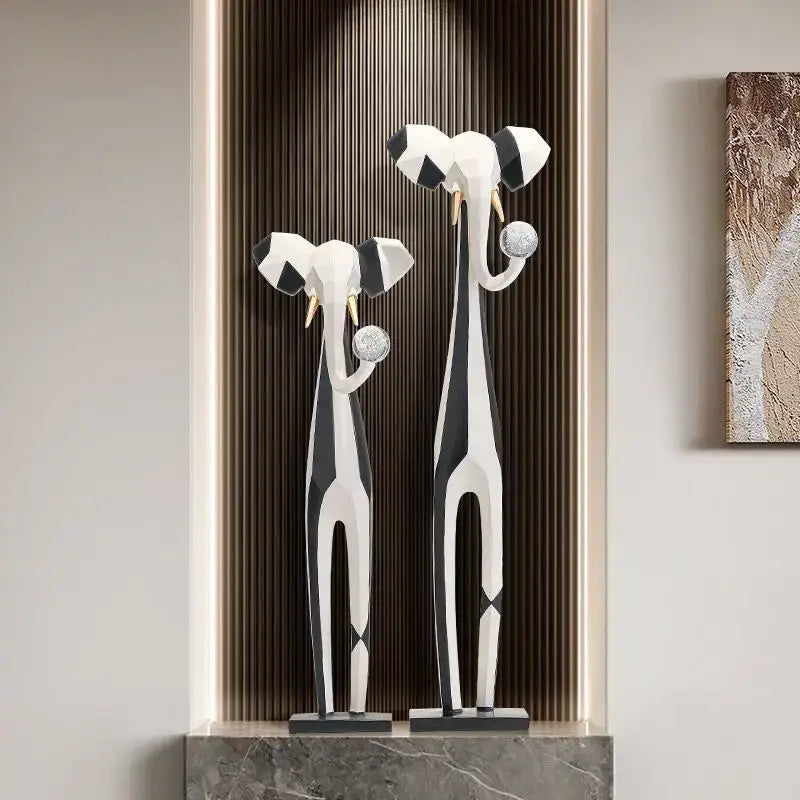 Stylized black and white elephant sculptures with gold tusks holding silver spheres for living room decorbites abstract art display
