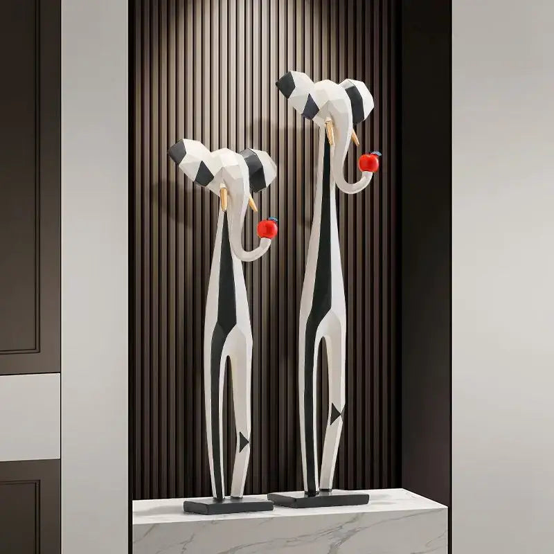 Two black and white striped elephant sculptures holding red apples in decorbites abstract art living room setup