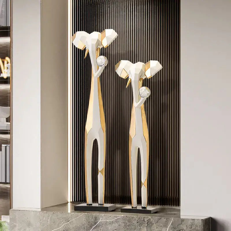 Two modern abstract art giraffe sculptures in white and gold holding crystal balls for decorbites living room decor