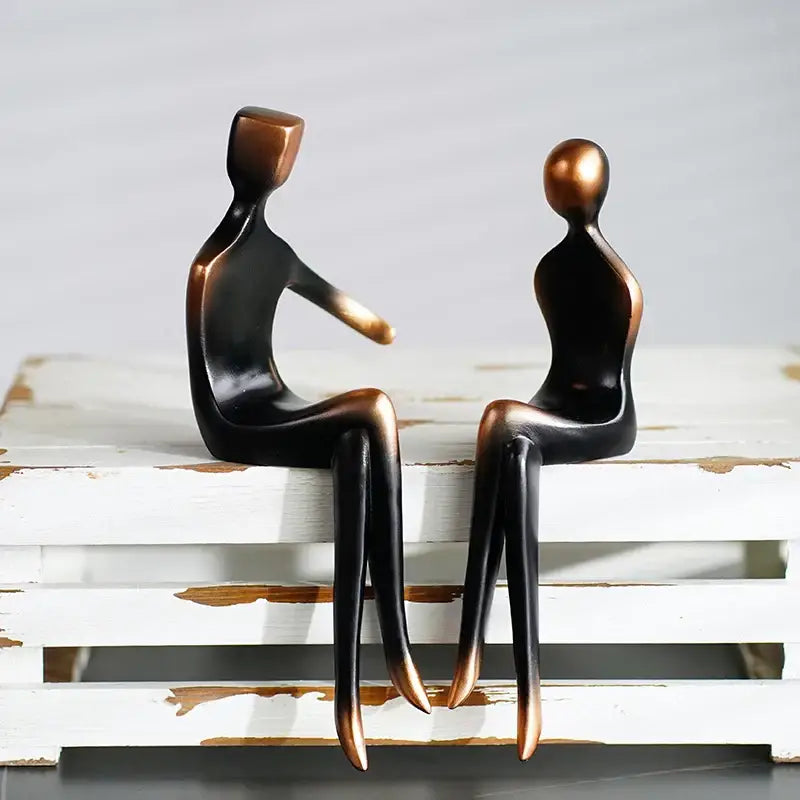 Bronze-colored resin abstract art figurines with square and round heads sitting on white surface decorbites abstract art