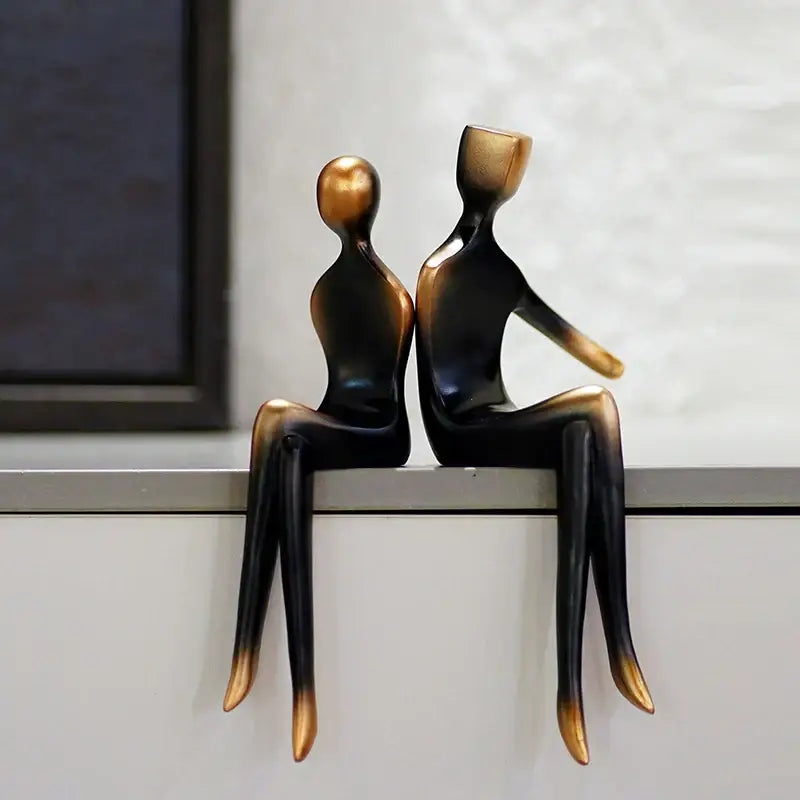 Two glossy black and gold resin figurines of seated abstract art lovers by DecorBites for Valentine’s anniversary gift