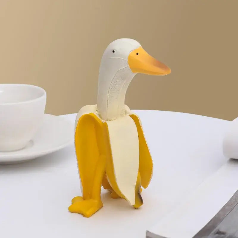 Whimsical white decorative figurine with yellow beak and feet designed as an abstract banana duck sculpture for decor