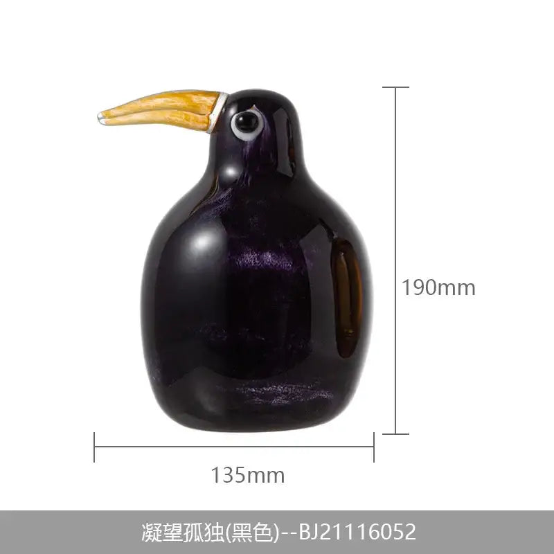 A glossy black ceramic decorbites abstract bird sculpture with a golden beak and silver ring for home decor