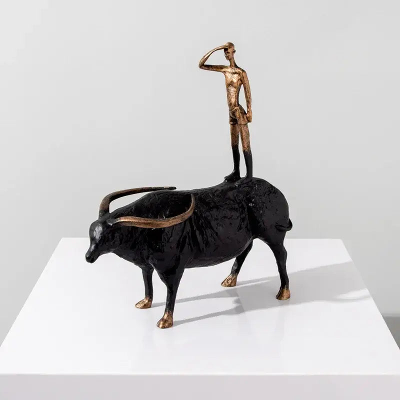 Bronze and black metal decorbites abstract black yak sculpture with stylized human figure saluting atop golden cow