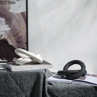 White decorbites abstract ceramic knot sculpture with smooth rounded forms resting on a book for room aesthetic decor