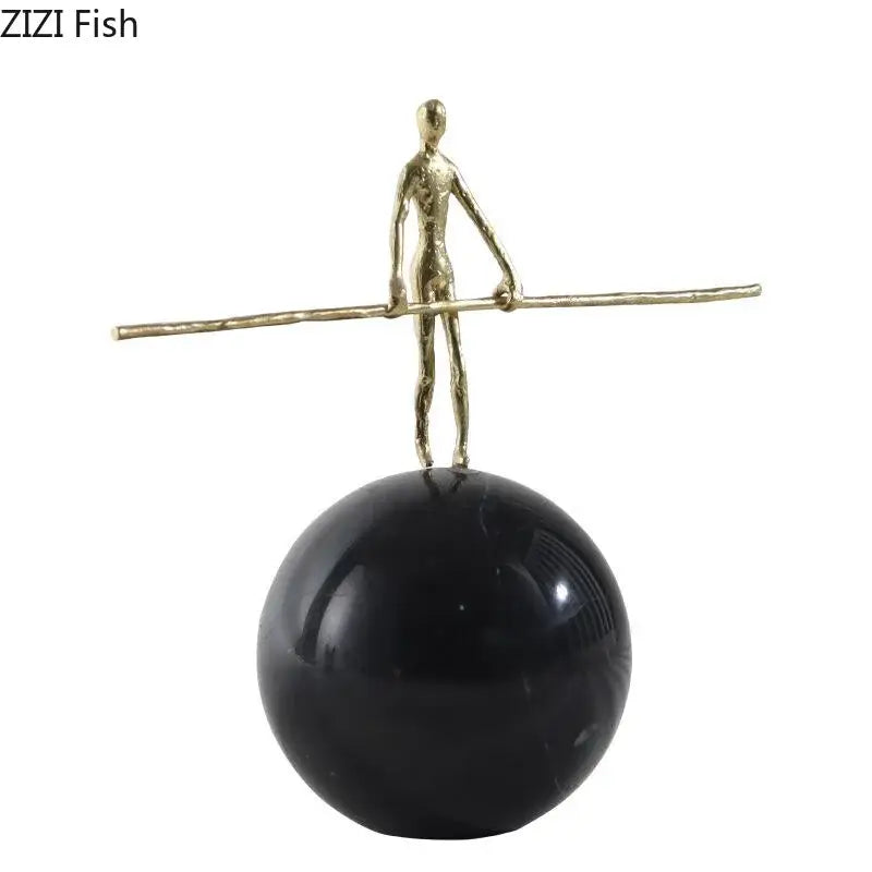 Gold-toned abstract character marble sculpture balancing on rod atop glossy black base for marble sculpture room decor