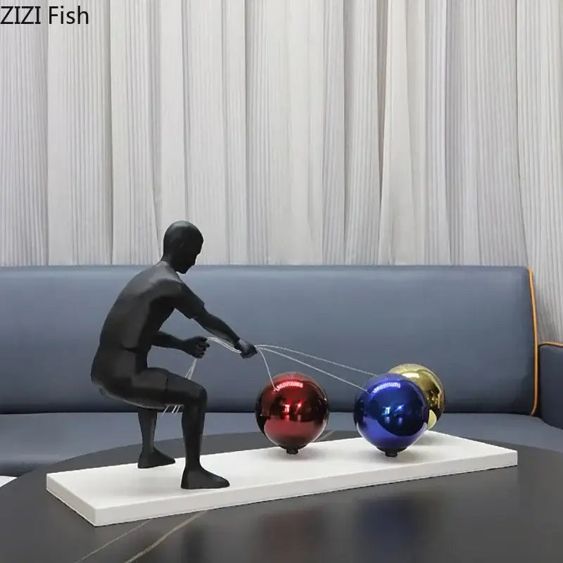 Black metal sculpture of abstract character pulling red blue and gold spheres decorbites abstract character desk ornament