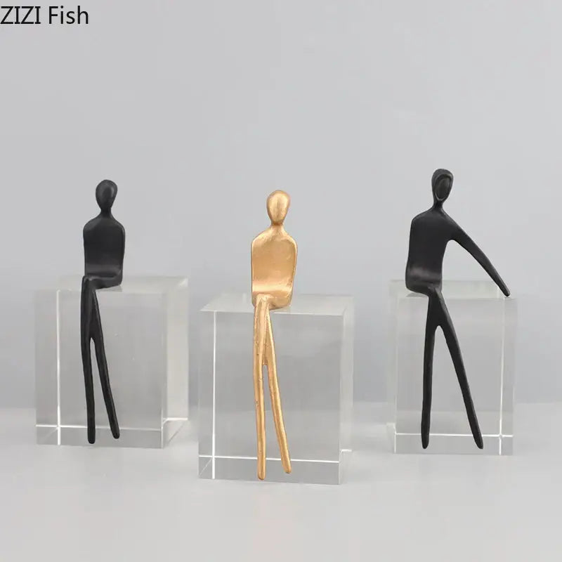 Decorbites abstract character sculpture featuring three minimalist black and gold-toned figurines on a crystal base