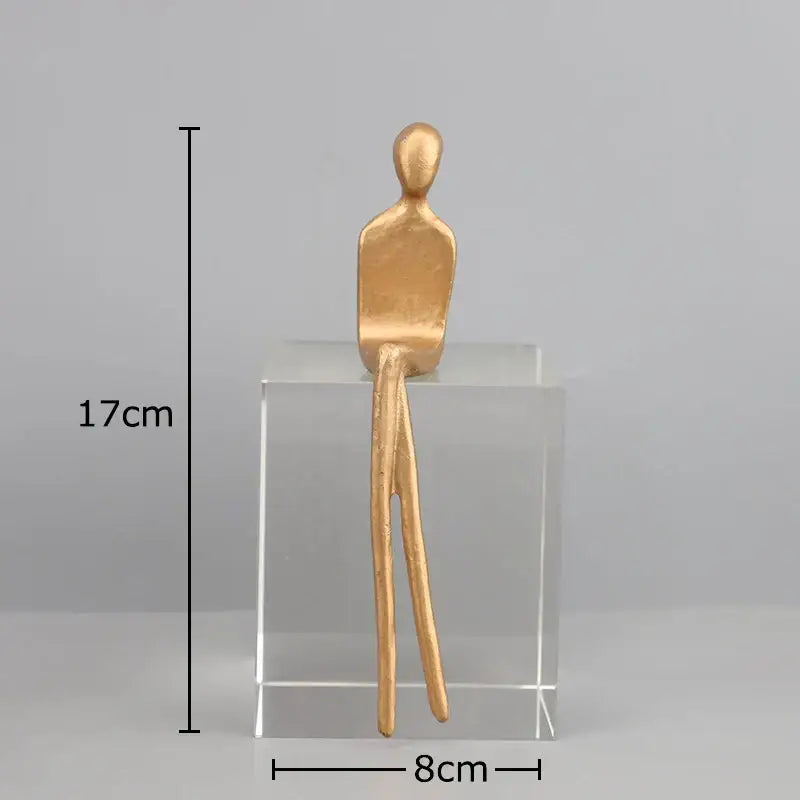 A minimalist gold-toned decorbites abstract character sculpture with elongated limbs and crystal base for modern decor