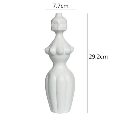 A sleek white ceramic vase shaped like a stylized female figure with sculpted contours decorbites abstract character
