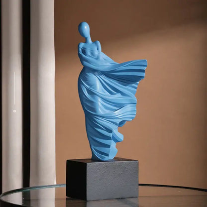 A sleek light blue resin decorbites abstract dancer figure sculpture with draped form on textured gray base