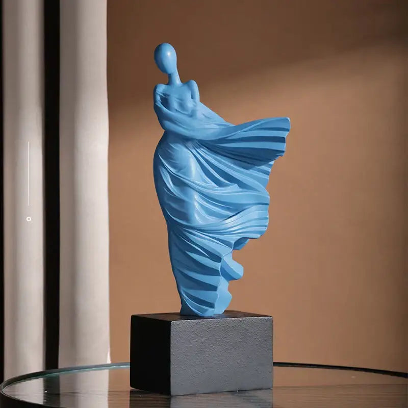 A sleek light blue resin decorbites abstract dancer figure sculpture with draped form on textured gray base