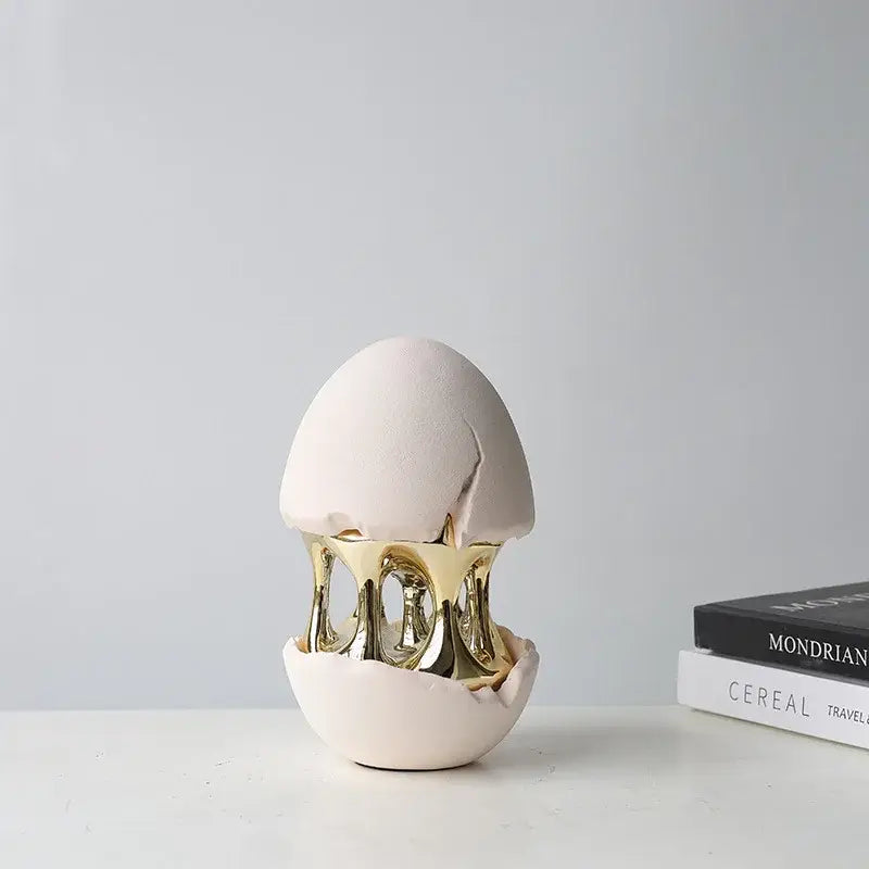 A sleek matte off-white ceramic decorative figurine with golden metallic interior decorbites abstract eggshell hollow design