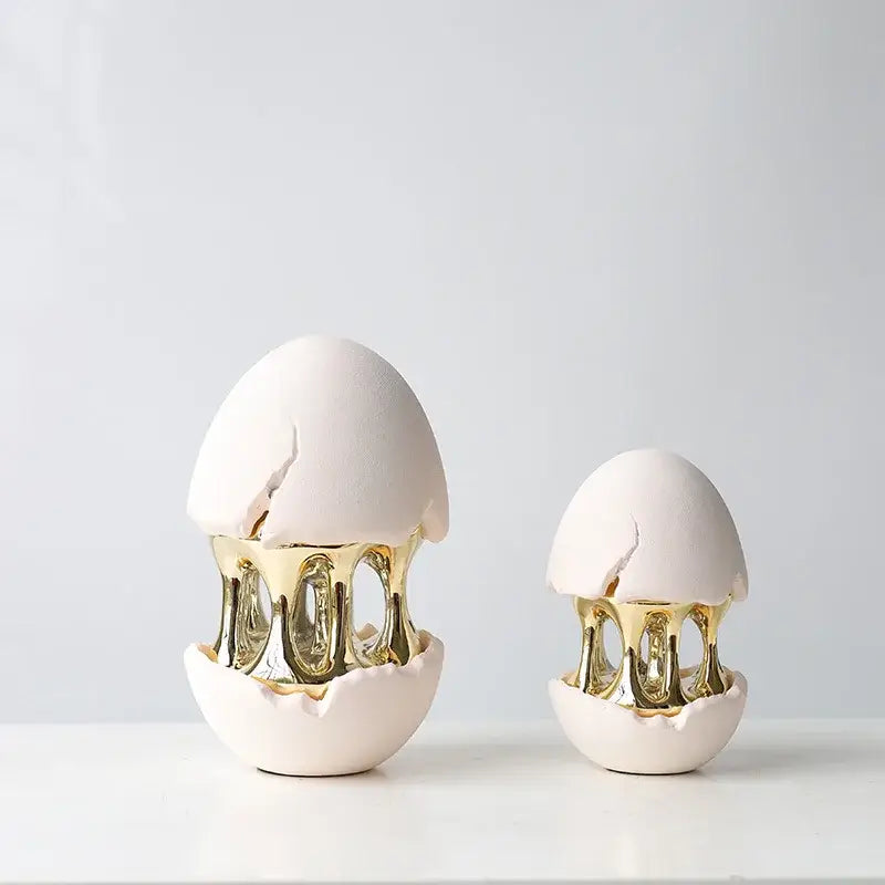 Two white ceramic decorative figurines with gold metallic interiors and cracked shells from DecorBites abstract eggshell hollow collection
