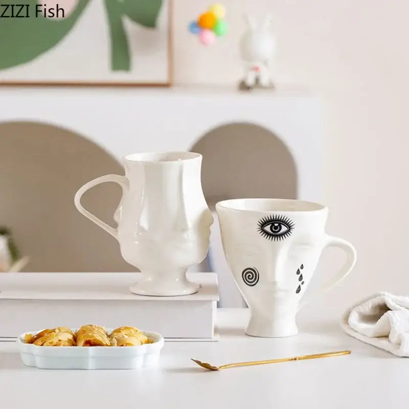 White ceramic mugs with decorbites abstract face black ink illustrations and sculpted abstract face ceramic design