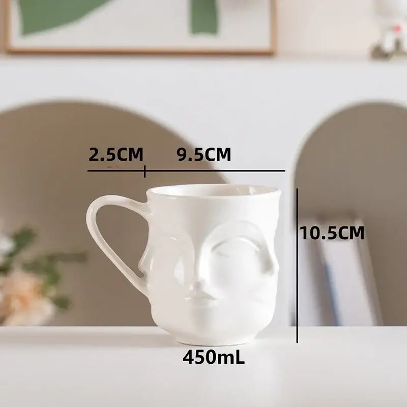 White ceramic mug with decorbites abstract face design and 450ml capacity for coffee and tea use