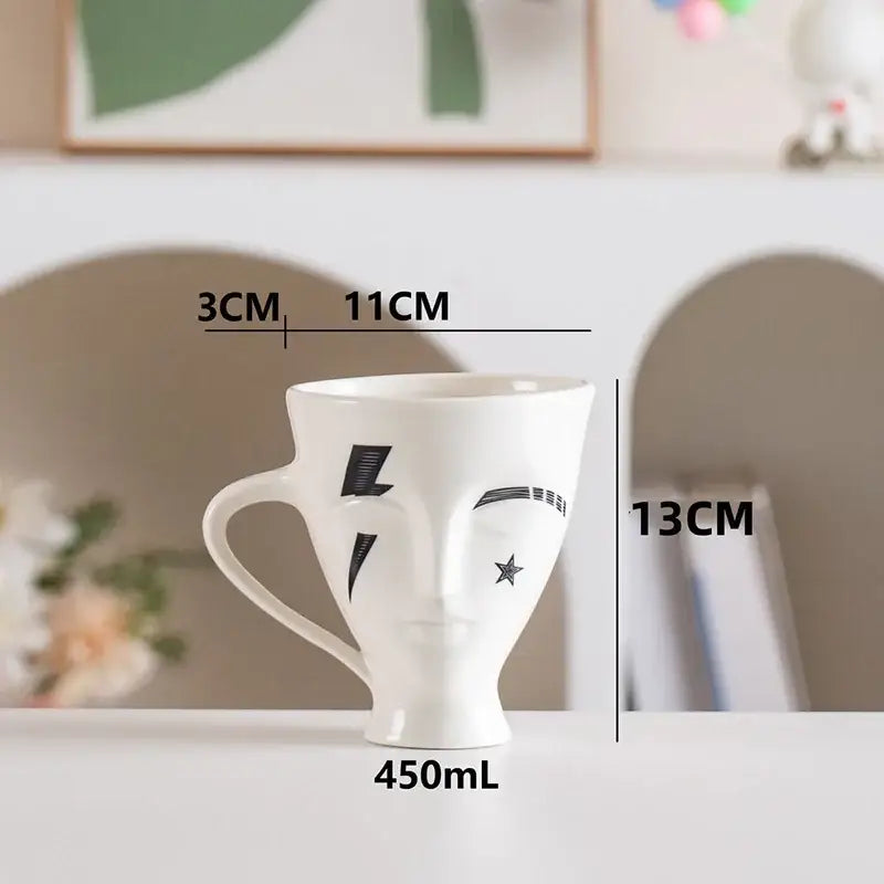 White ceramic mug with black decorbites abstract face design featuring lightning bolts and star 450ml capacity