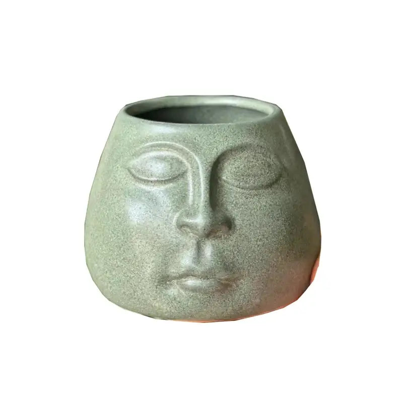 A matte gray decorbites abstract face ceramic planter shaped like a serene face with closed eyes for home decor