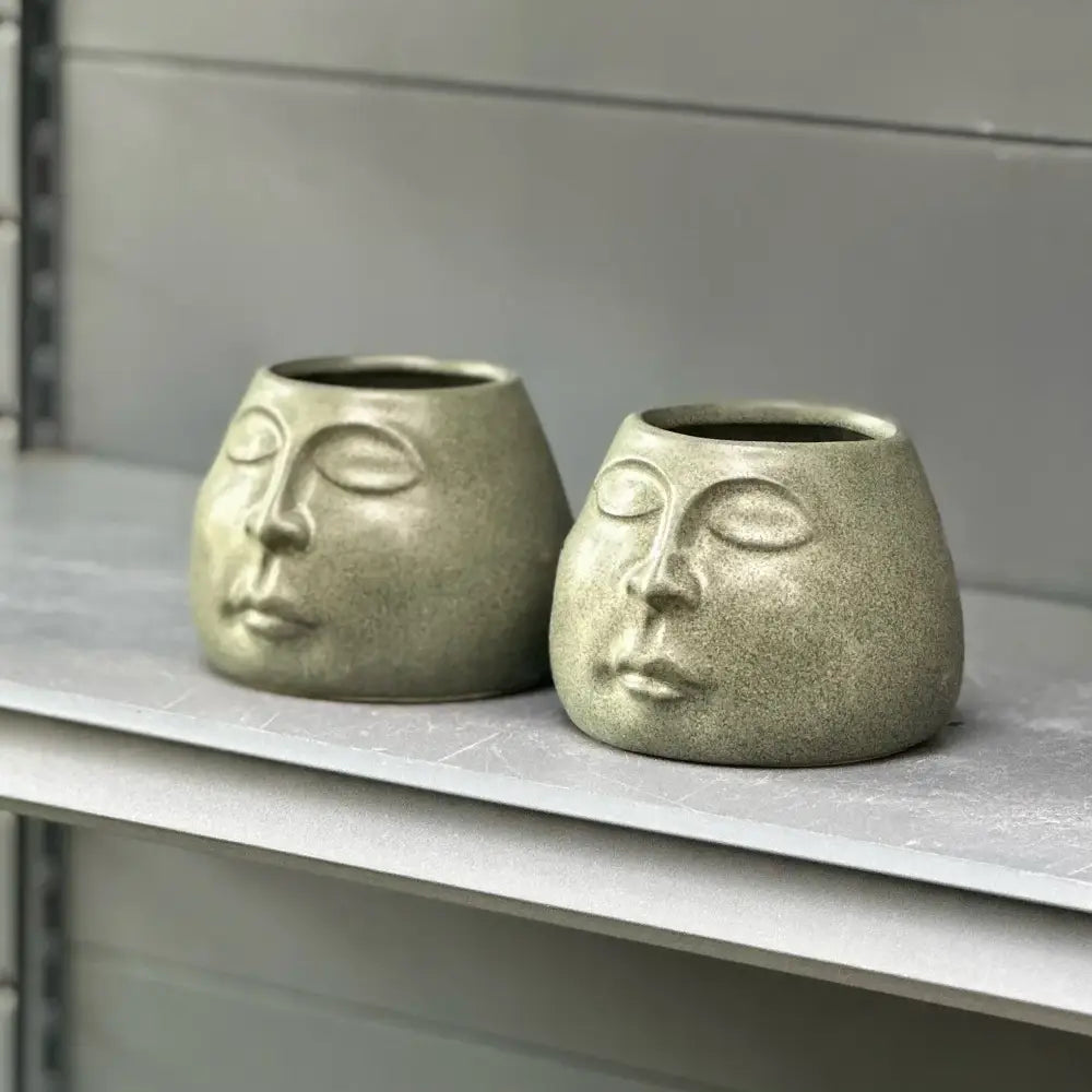 Two sage green decorbites abstract face ceramic planters with serene closed eyes for home decor accessories