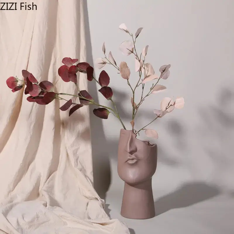 A matte mauve decorbites abstract face ceramic vase shaped like a stylized human head for table flower decoration
