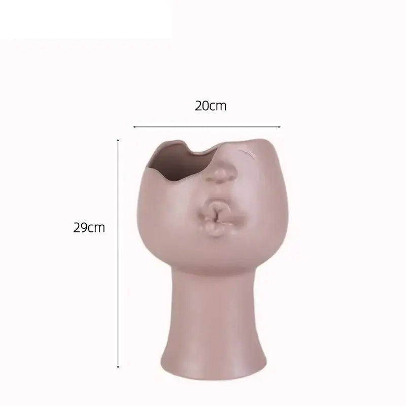 A matte blush pink abstract face ceramic planter by decorbites shaped as a stylized head with an open mouth planting hole