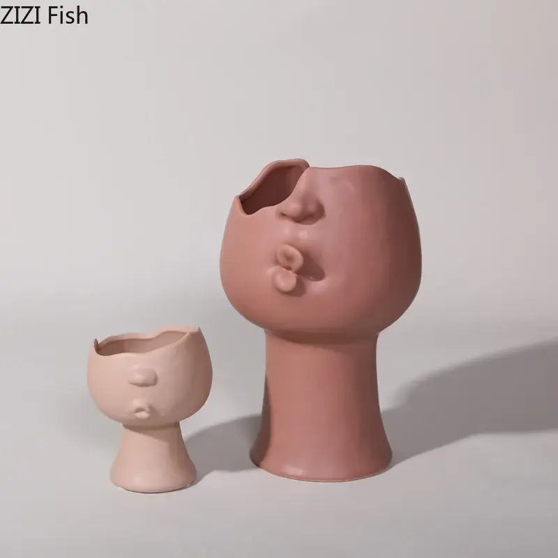 A pair of blush pink decorbites abstract face ceramic vases with sculpted features and cracked top design for table flowers