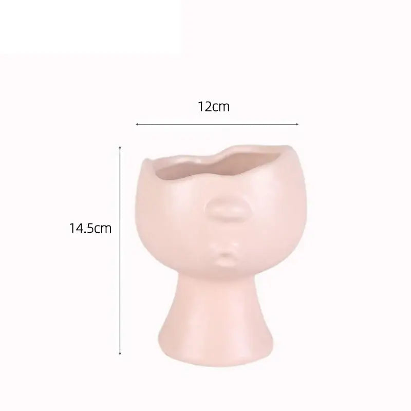 A blush pink decorbites abstract face ceramic planter featuring stylized lips and nose for table flower decoration