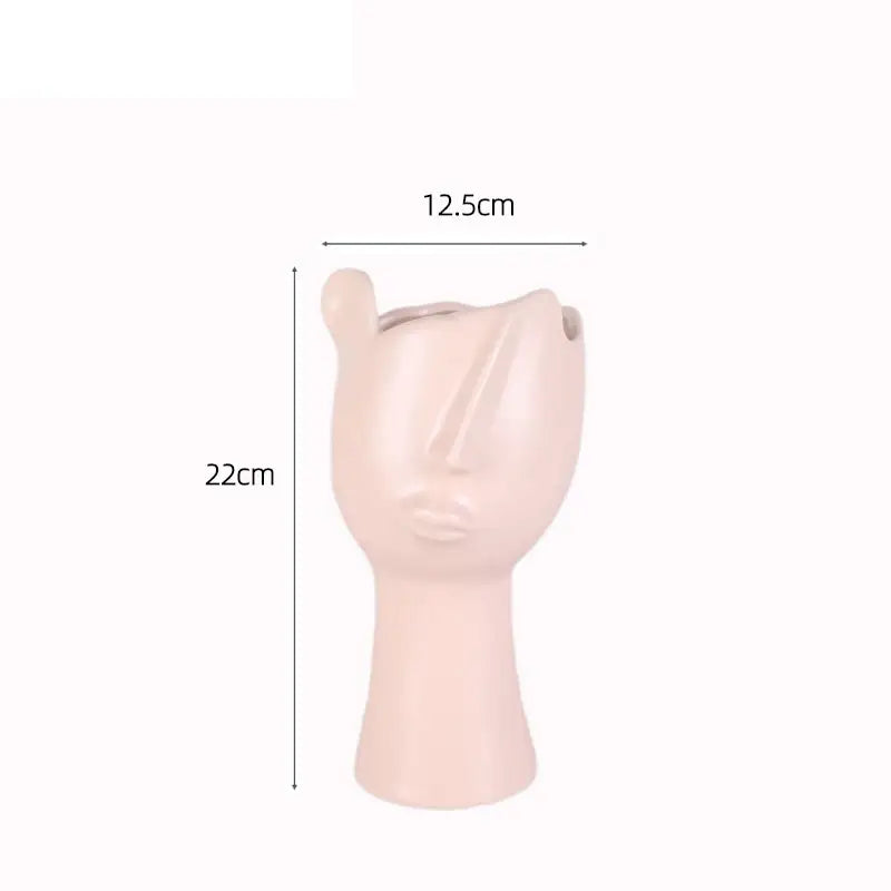 A blush pink ceramic planter shaped like an abstract face with defined features from decorbites abstract face collection