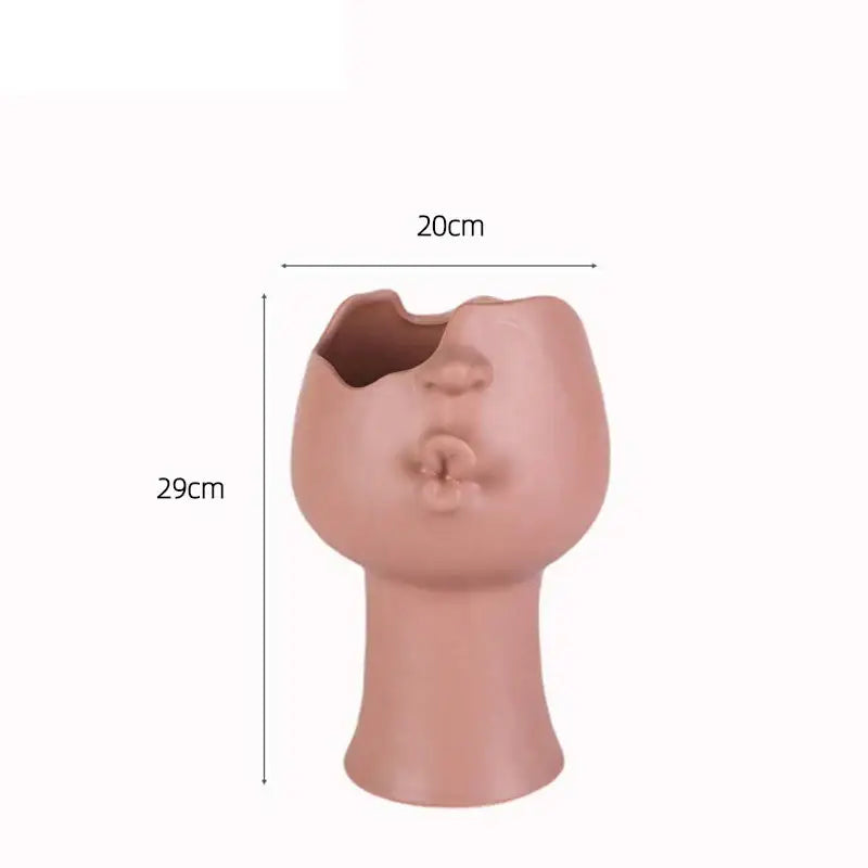 A terracotta-colored abstract face ceramic planter with an open mouth by decorbites for table flower decoration