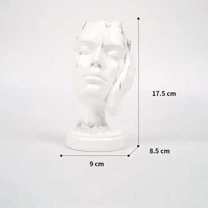 White ceramic decorbites abstract face mask sculpture with cracked features and tears on circular base for home decor