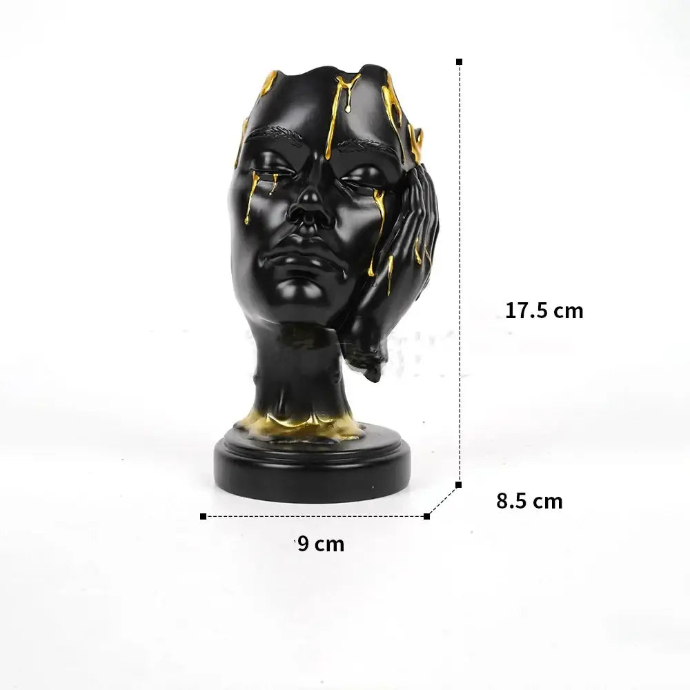 Black resin decorbites abstract face mask sculpture with gold drips and hand on cheek for home decor display