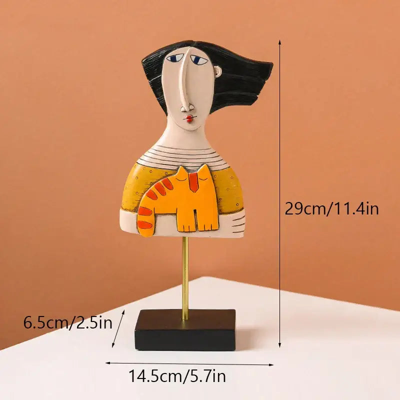 Stylized ceramic figurine of a woman holding an orange cat in a yellow top decorbites abstract face resin art ornament