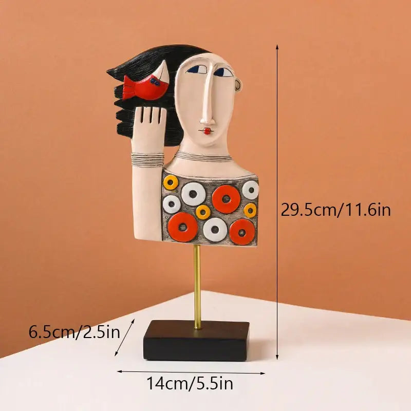 A stylized ceramic woman figurine with black hair red lips and orange white geometric patterns in decorbites abstract face resin art
