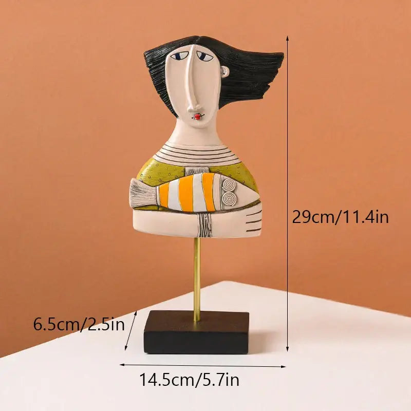 Decorbites abstract face resin art figurine of woman with black hair in green top holding orange and white fish for decor