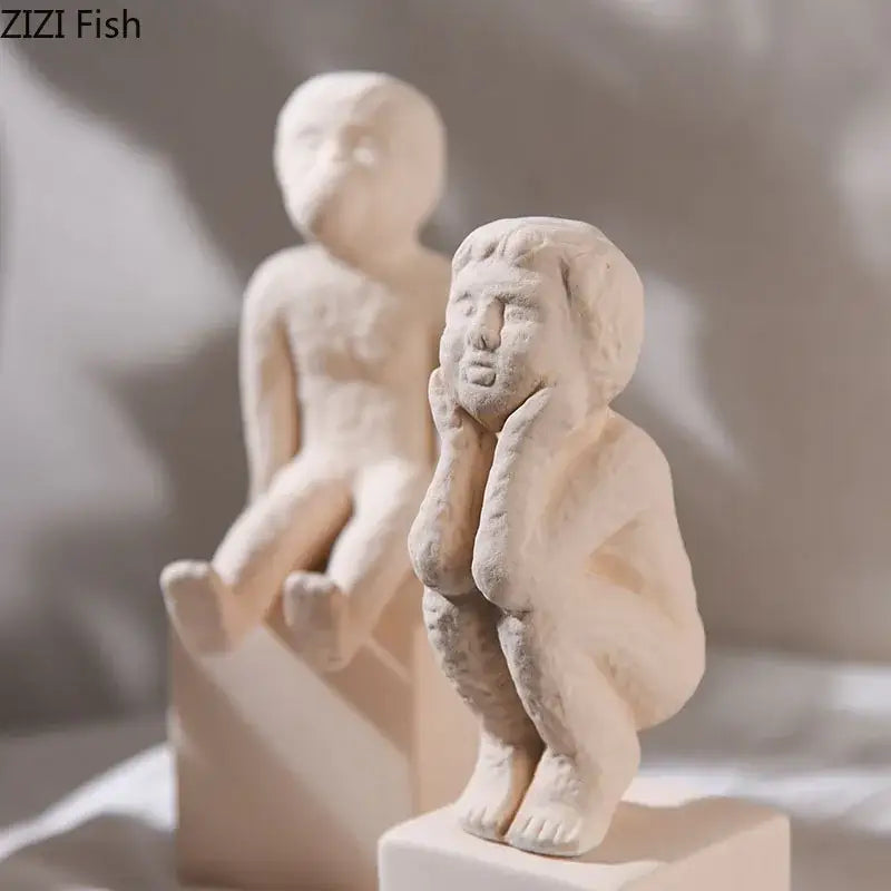 Cream-colored ceramic decorbites abstract family character figurine of child sitting with hands on cheeks for desk decor