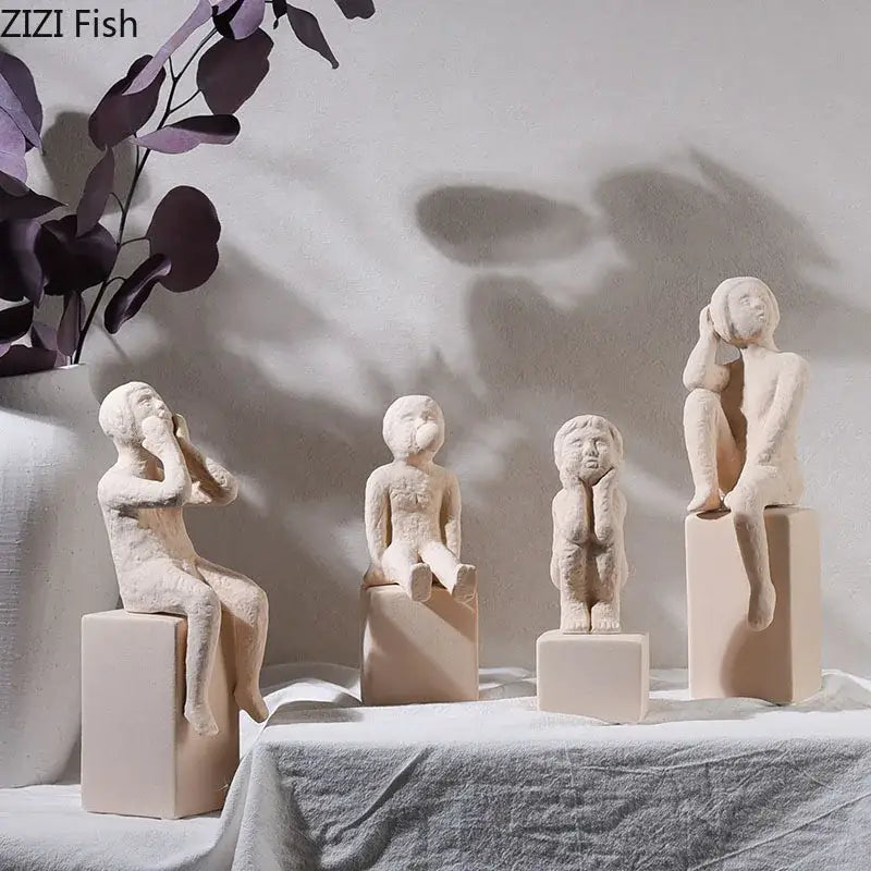 Four minimalist ceramic figurines depicting children in seated poses on square bases from decorbites abstract family character sculpture
