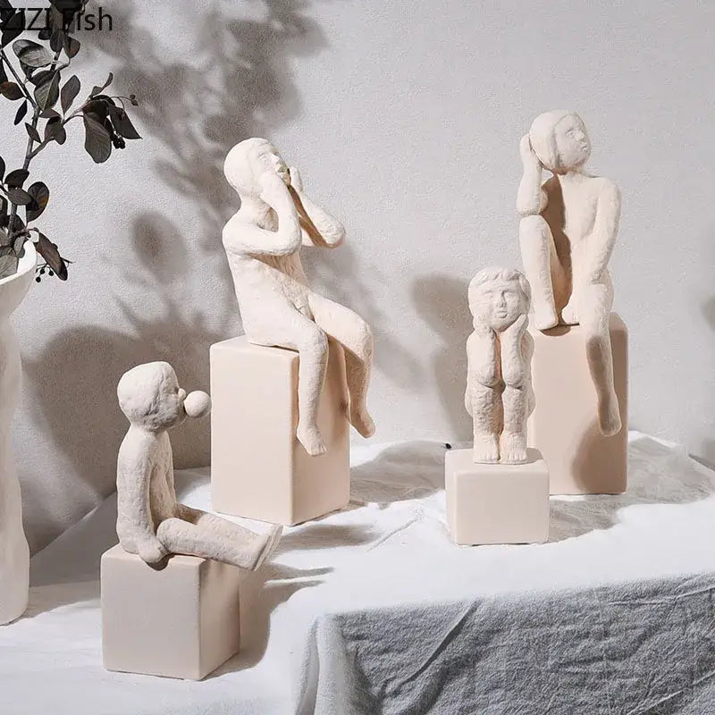 Cream-colored decorbites abstract family character ceramic sculptures of children seated on matching cube bases for desk decor