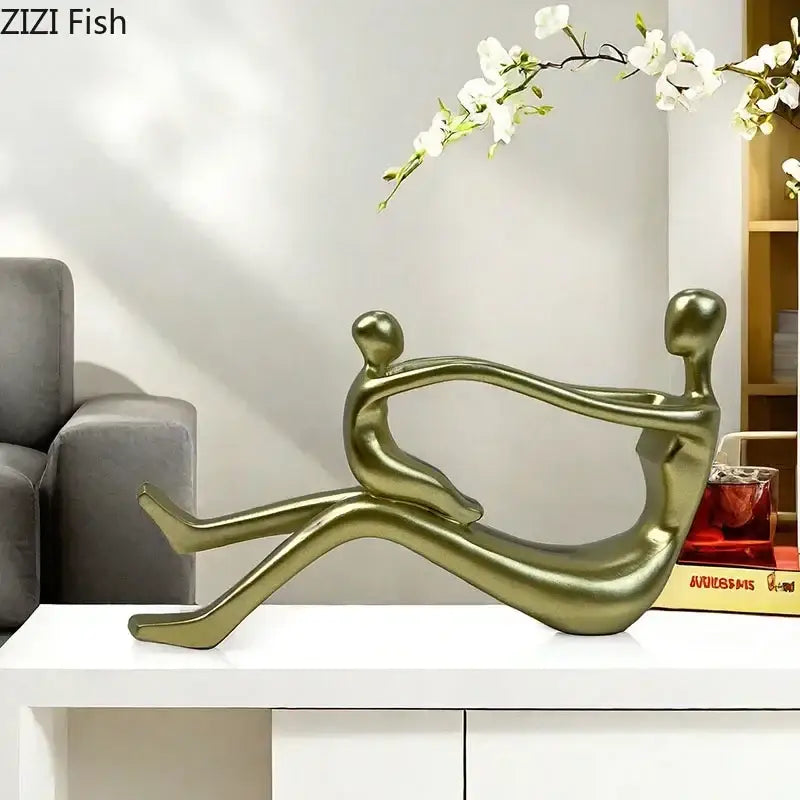 Gold-colored decorbites abstract family resin sculpture of two intertwined human figures in a reclining pose for decor
