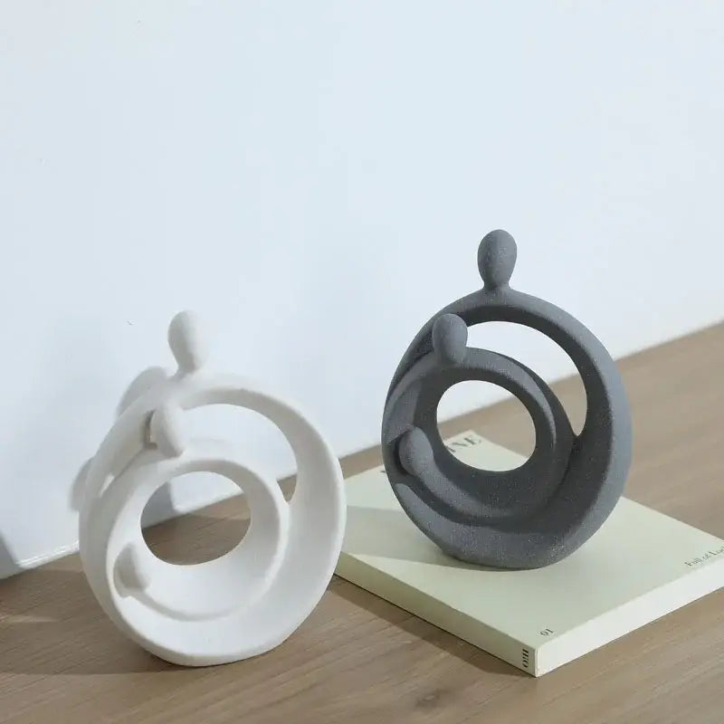 Two minimalist white and gray ceramic figurines with circular rings in decorbites abstract family sculpture set