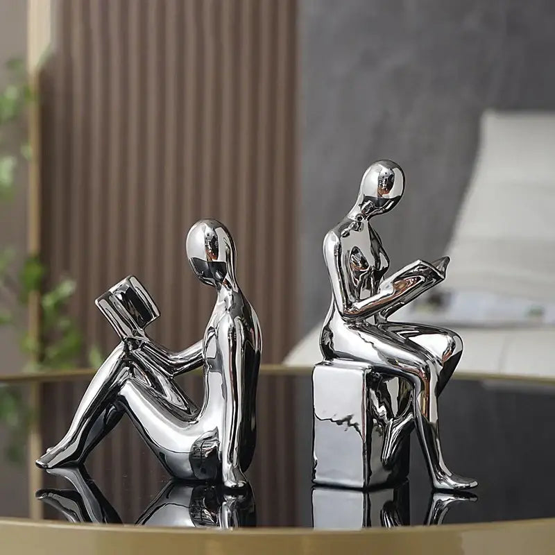 Two chrome-finished DecorBites abstract figure bookend set featuring sleek seated forms reading books for stylish decor