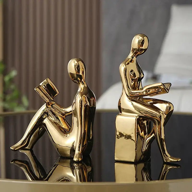 Two golden glossy decorbites abstract figure bookend set depicting seated human forms reading books for home decor