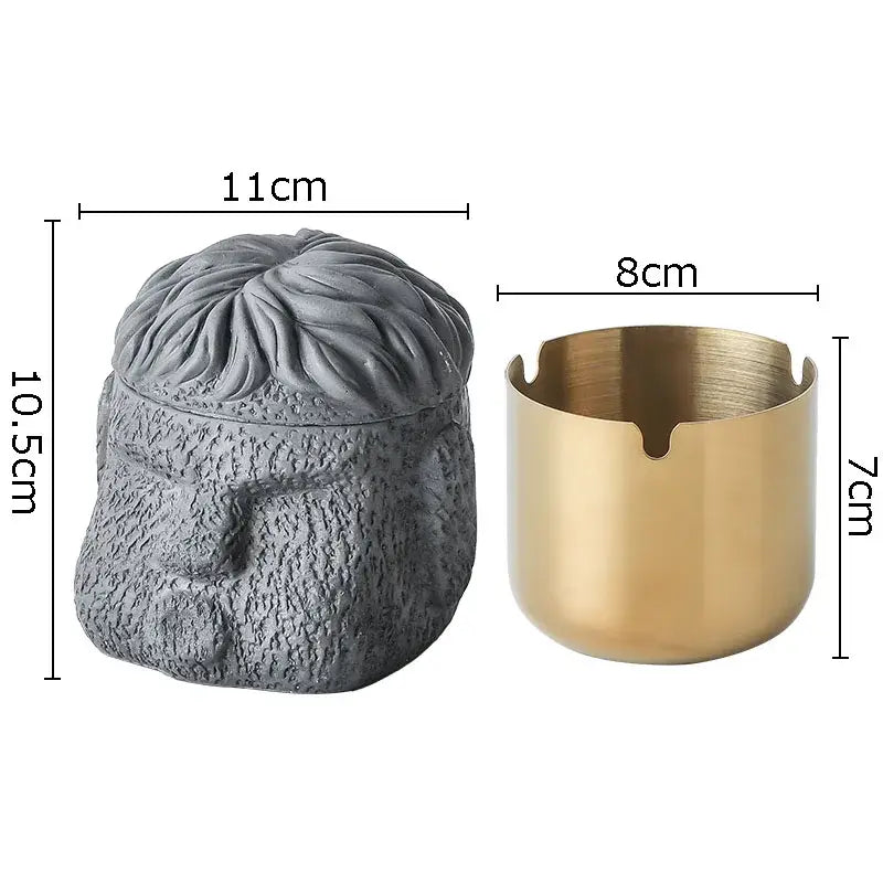 Decorbites™ abstract figure portraits cement ashtray shaped like a bearded man head next to a gold metal ashtray