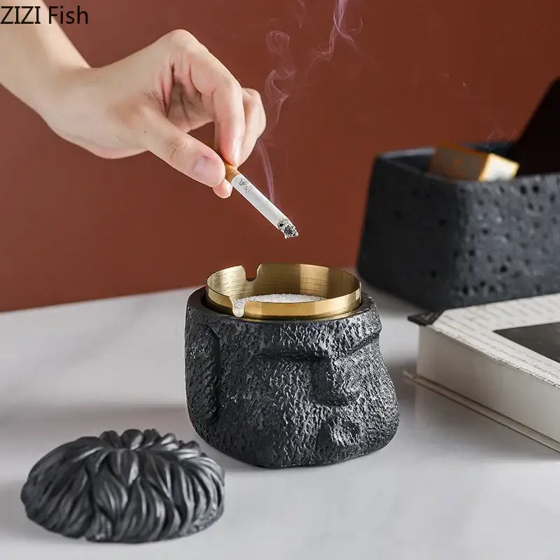 Black textured ashtray with gold rim and lid designed as a stone head for decorbites™ figure portraits cement collection