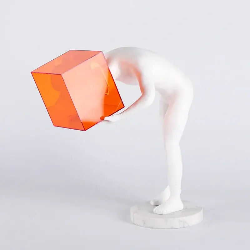 White figurine holding an orange translucent cube in decorbites cage human body mind abstract sculpture