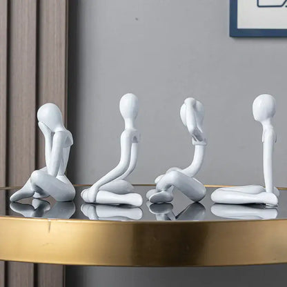 Four minimalist white ceramic decorbites abstract figures ornament sculpture in distinct seated poses for home decor