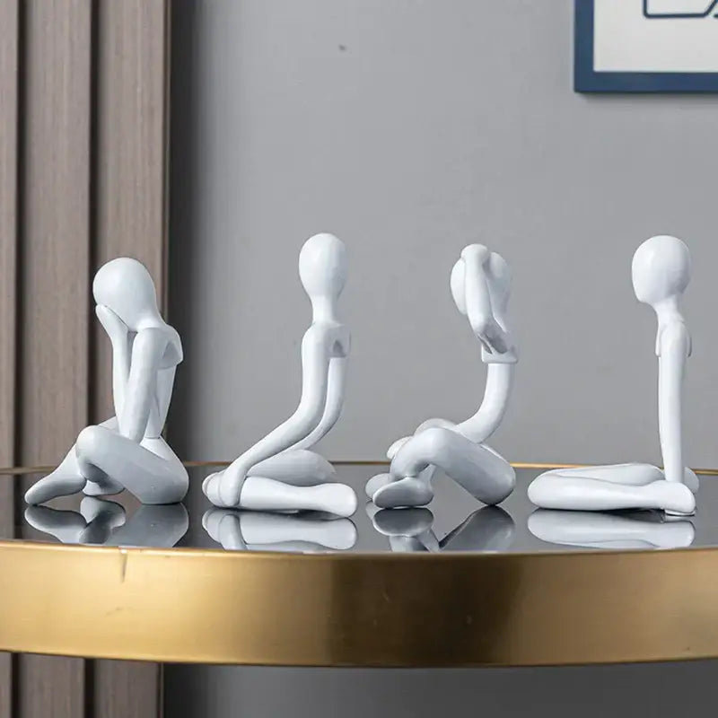 Four minimalist white ceramic decorbites abstract figures ornament sculpture in distinct seated poses for home decor