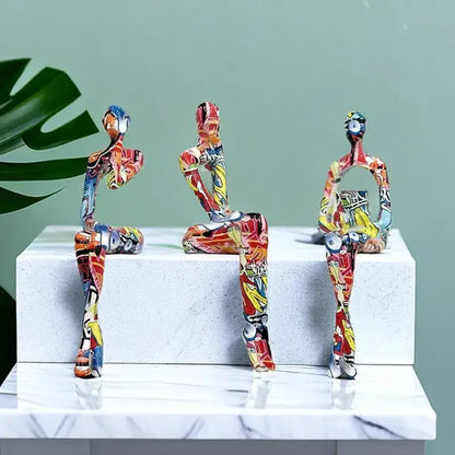 Three vibrant red yellow and blue decoBites abstract figurine modern pop art sculptures on white marble pedestal for home decor
