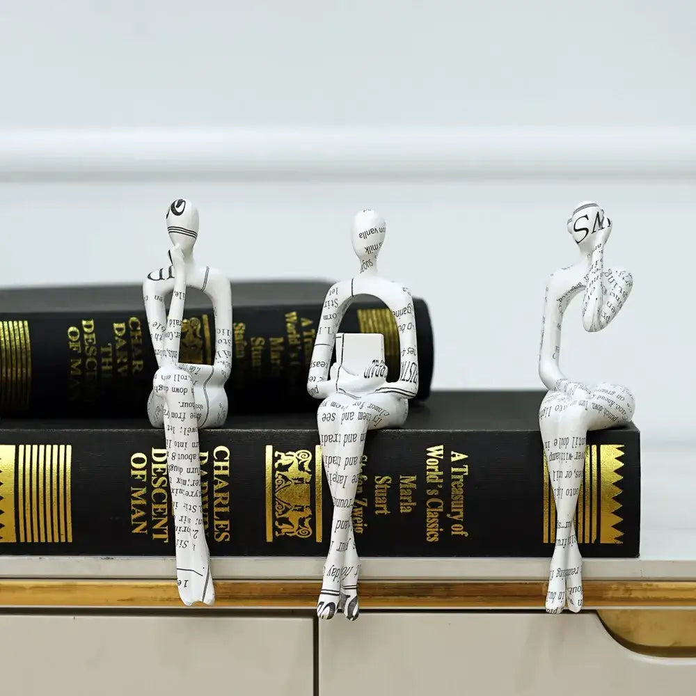 Three white paper-textured decorbites abstract figurine modern sculptures with black text seated on stacked books for home decor